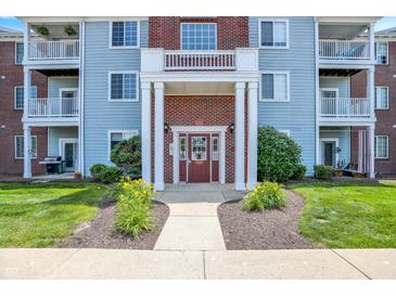 Attractive condo complex featuring brick accents, white pillars, green grass, blue siding, and a central entryway at 5011 Amber Creek Pl # 310, Indianapolis, IN 46237