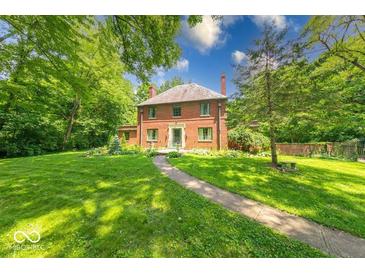 Charming brick two-story home with mature trees and a well-manicured lawn. The house has a walkway and multiple windows at 6125 N Olney St, Indianapolis, IN 46220