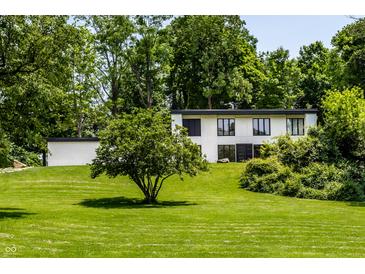 An exterior view of a modern home with a white facade, black trim and verdant lawns and landscaping at 6164 Afton Crest, Indianapolis, IN 46220