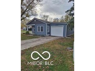 Charming single-story home featuring blue siding, a front porch, attached garage and a well-maintained lawn at 1321 Lennox St, Anderson, IN 46012