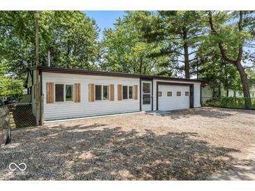 Exterior of home with vinyl siding and garage door nestled amongst mature trees and gravel driveway at 3529 Hunt St, Plainfield, IN 46168
