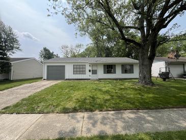 Charming home featuring a well-maintained lawn, gray accents, and mature trees, creating a welcoming curb appeal at 7641 E 35Th St, Indianapolis, IN 46226