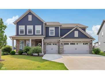 Inviting two-story home boasts a three-car garage, manicured lawn, and classic blue siding at 9671 Ridgecrest Ln, McCordsville, IN 46055