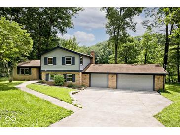 Two-story home with brick accents and a three-car garage surrounded by lush greenery at 3545 Whippoorwill Lake N Dr, Monrovia, IN 46157