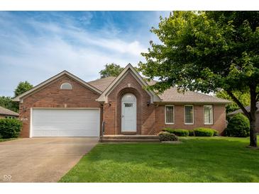 Charming brick home with a well-manicured lawn, an arched entryway, and an attached two-car garage at 5032 Monticello Dr, Columbus, IN 47203