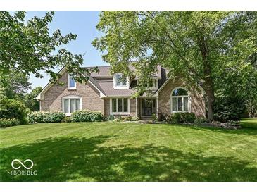 Charming brick home featuring lush landscaping, mature trees, and well-maintained lawn at 11030 Brentwood Ave, Zionsville, IN 46077
