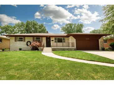 Charming ranch home with a manicured lawn, quaint walkway, and attached garage at 5927 Meadowood Dr, Speedway, IN 46224
