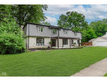 Charming home with stone accents, covered entryway, lush lawn, and mature trees at 12118 Castle Row Overlook, Carmel, IN 46033