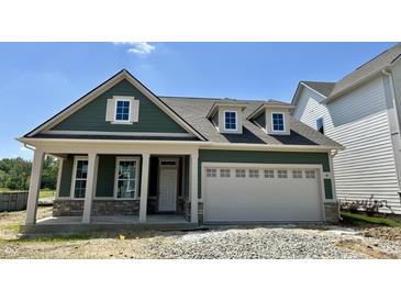 Charming green home boasts a stone-accented facade and a convenient two-car garage, offering curb appeal and practicality at 14277 Coyote Rdg, Noblesville, IN 46060
