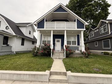Charming two-story home featuring a covered front porch, white columns, and a well-maintained lawn with flowers at 1720 Rembrandt St, Indianapolis, IN 46202