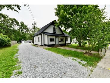 Charming home featuring a gravel driveway, contrasting black and white color scheme, and mature trees at 2801 E Southport Rd, Indianapolis, IN 46227