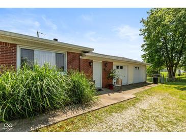 Exterior view featuring an oversized garage, white doors, and manicured landscaping at 5719 N Frontage Rd, Fairland, IN 46126