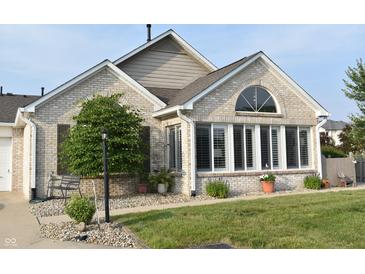 Charming brick home featuring a well-manicured lawn, trimmed shrubs, and a cozy front porch at 7357 Lake Lakota Dr, Indianapolis, IN 46217