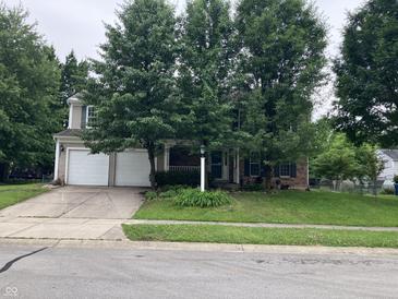 Charming two-story home featuring a well-maintained front yard with mature trees and a two car garage at 7667 Madden Ln, Fishers, IN 46038