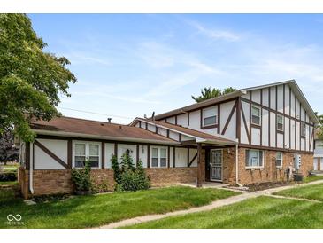 Charming townhome featuring a well-manicured lawn, brick accents, and a welcoming front porch at 10016 Penrith Dr, Indianapolis, IN 46229