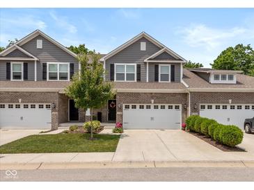 Charming townhome featuring a brick facade, attached garage, and well-manicured lawn at 14442 Treasure Creek Ln, Fishers, IN 46038