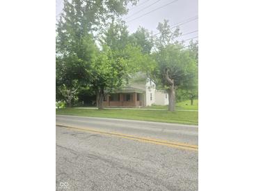 Traditional two-story home with a brick porch and mature trees providing shade and curb appeal at 9024 W Mooresville Rd, Indianapolis, IN 46113