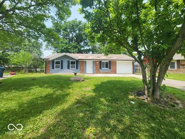 Charming single-story home with a manicured lawn and mature trees providing shade at 9526 Burrwood Ct, Indianapolis, IN 46235