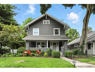 Charming two-story home with beautifully landscaped front yard featuring colorful flowers and lush greenery at 5922 Broadway St, Indianapolis, IN 46220