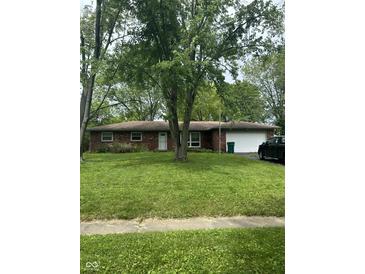 Charming brick home featuring an attached garage and a well-maintained front yard with mature trees at 8312 Lamira Ln, Indianapolis, IN 46234