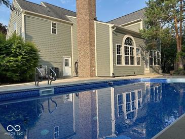 Back of home featuring an in-ground pool with blue water and reflection of the home's architecture at 13262 Landwood Dr, Fishers, IN 46037