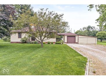 Charming ranch-style home featuring a well-manicured lawn, mature tree, and a convenient attached garage at 4010 S Bazil Ave, Indianapolis, IN 46239