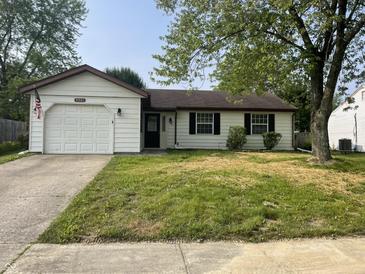 Charming one-story home with a well-kept lawn, attached garage, and an American flag waving at 5331 Yucatan Dr, Indianapolis, IN 46237