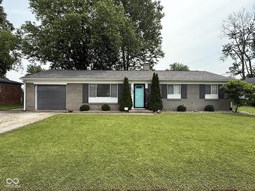Charming one-story home with a well-manicured lawn, gray brick facade, and an inviting blue front door at 729 Maple Ln, Brownsburg, IN 46112