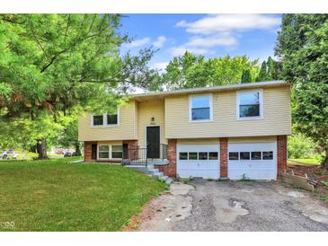Split-level home featuring a two-car garage, siding, and landscaped front yard at 8920 Caminito Rd, Indianapolis, IN 46234