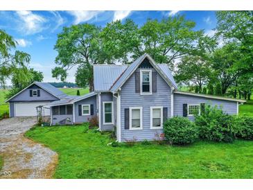 Charming two-story home with blue siding, well-maintained lawn, and mature trees, offering a peaceful setting at 9237 N 500 W, Fountaintown, IN 46130
