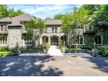 Stunning stone home featuring arched entry, balconies, and mature landscaping at 11557 Willow Springs Dr, Zionsville, IN 46077