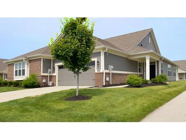 Inviting front yard and entrance of a gray and brick home with a well manicured green lawn at 17303 Lillian St, Westfield, IN 46074