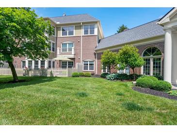 Beautifully landscaped backyard features a lush lawn, mature trees, and architectural details at 7601 Newport Bay Dr # 115, Indianapolis, IN 46240