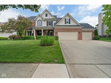 Charming two-story brick and white home with a well-manicured lawn and a three-car garage at 8904 Carnation Dr, Noblesville, IN 46060