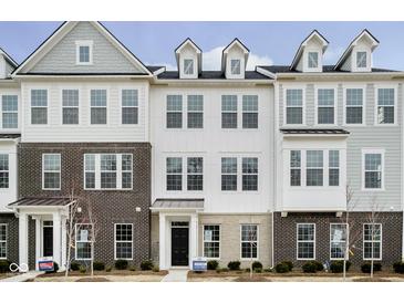 Modern townhome featuring a brick and white facade with large windows and a welcoming entrance at 14521 Hanford Ln, Carmel, IN 46074