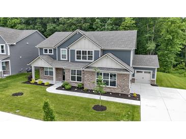 Beautiful two-story home boasts a brick facade, attached garage, and a well-manicured lawn with mature trees at 15546 Senita Ln, Fishers, IN 46037