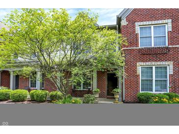 Charming brick home with lush landscaping, including a mature tree and manicured bushes at 6691 Beekman Pl, Zionsville, IN 46077