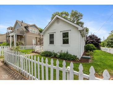 Charming cottage-style home featuring a classic white picket fence and well-maintained lawn and landscaping at 905 Buchanan St, Indianapolis, IN 46203
