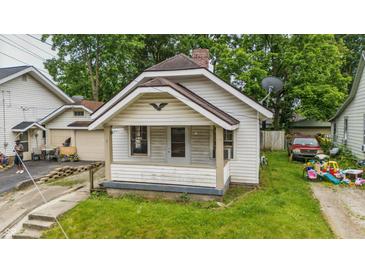 Charming home featuring a covered front porch, brick chimney, and a compact yard needing some attention at 1011 W 7Th St, Anderson, IN 46016