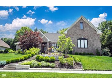 Charming brick home featuring lush landscaping, a stone walkway, and a well-maintained lawn at 10707 Burning Ridge Ln, Fishers, IN 46037