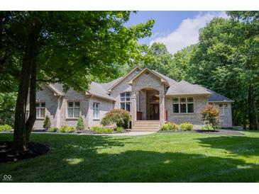 Charming brick home with manicured lawn, blooming flowers, and a covered front porch entrance at 23119 Sonoma Ln, Cicero, IN 46034
