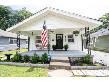 Charming home featuring a quaint covered porch, adorned with an American flag and seating area at 4927 Caroline Ave, Indianapolis, IN 46205