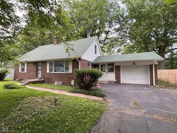 Charming brick home with a well-maintained lawn, attached garage, and mature trees at 5460 N Park Dr, Indianapolis, IN 46220