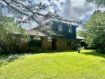 View of a beautiful brick two-story home with a well-manicured lawn and partial tree coverage at 8875 N Goat Hollow Rd, Mooresville, IN 46158