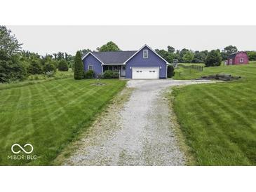 Charming blue home with a two-car garage, spacious yard, and a long gravel driveway at 911 Centennial Rd, Martinsville, IN 46151