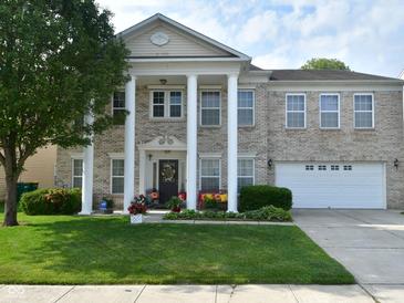 Charming two-story home features a columned porch, attached garage, and well-maintained lawn at 10601 Adam Dr, Indianapolis, IN 46231