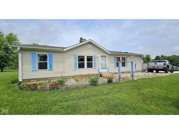 Charming single-story home with light siding, blue shutters, and a well-maintained front lawn and colorful flower bed at 10694 W Hickory Ct, Quincy, IN 47456