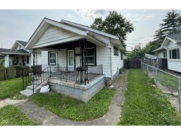 View of a modest white home with a small porch and wrought iron railings, needing some TLC and landscaping at 1226 Hiatt St, Indianapolis, IN 46221
