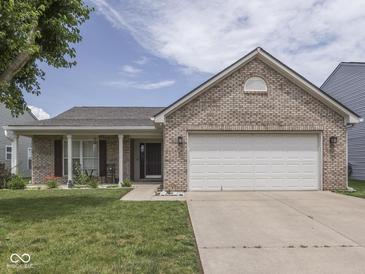 Charming brick home featuring an attached two-car garage, a cozy front porch, and a well-maintained lawn at 2734 Newaygo Dr, Indianapolis, IN 46217