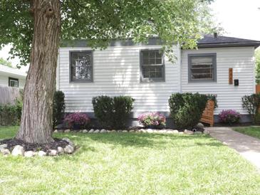 Charming home featuring a landscaped front yard with flowering bushes and a large shade tree at 4445 Kingsley Dr, Indianapolis, IN 46205